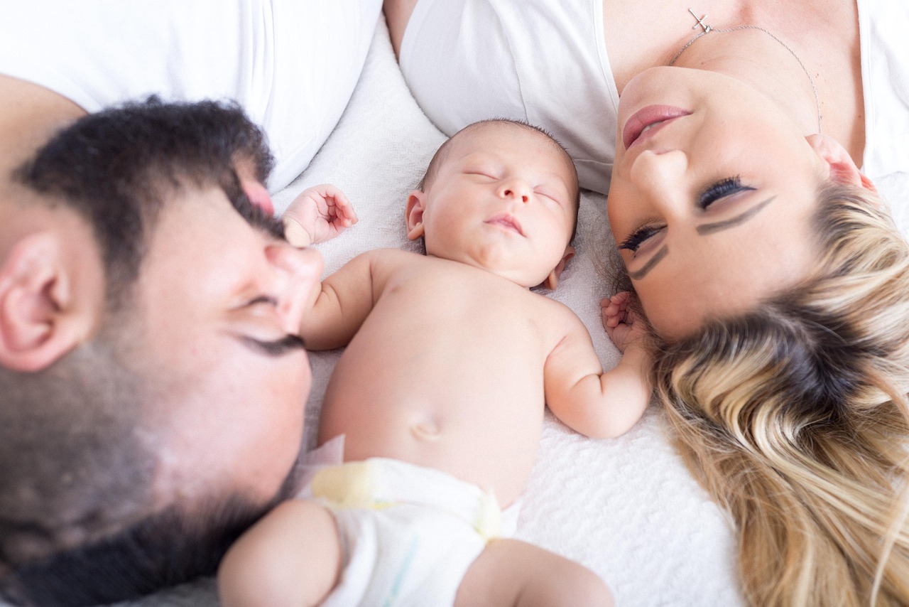 A beautiful child is sleeping while their parents look at them with love and joy. By Social Mom Blog
